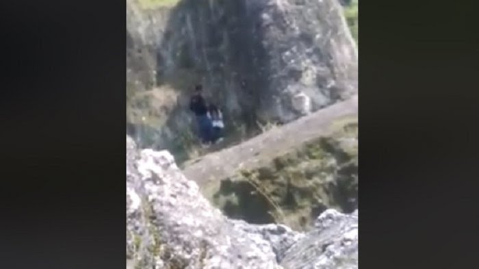 Si Wanita Jongkok Si Pria Lakukan Ini Sambil Goyang-goyang di Tepi Tebing