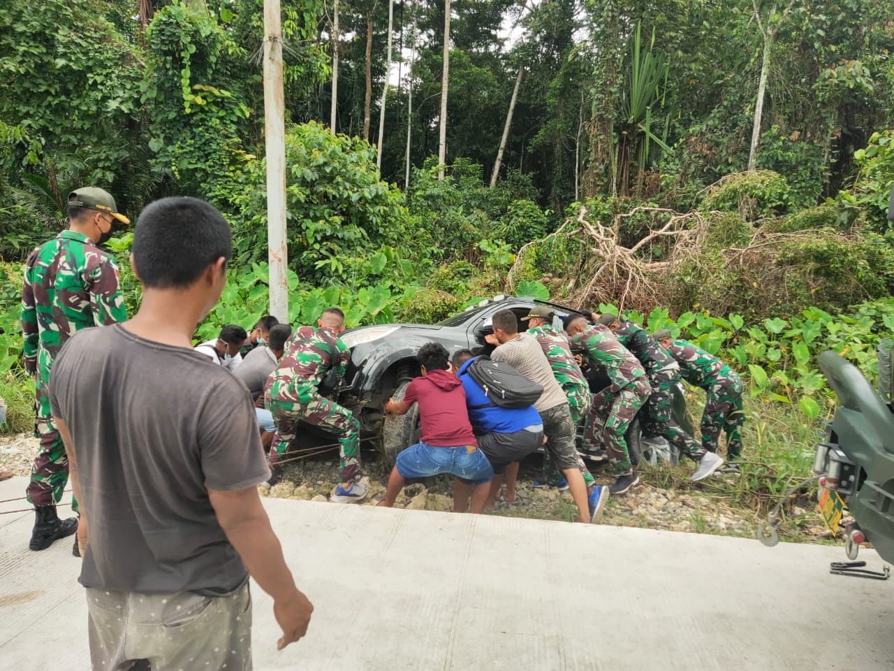Personel Satgas Pamtas Yonif 131/Brs Bantu Evakuasi Mobil Warga Yang Terguling